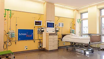 Krankenbett mit Monitoren, Infusionssystemen und medizinischen Anschlüssen in einem Einzelbereich der Intensivobservation.