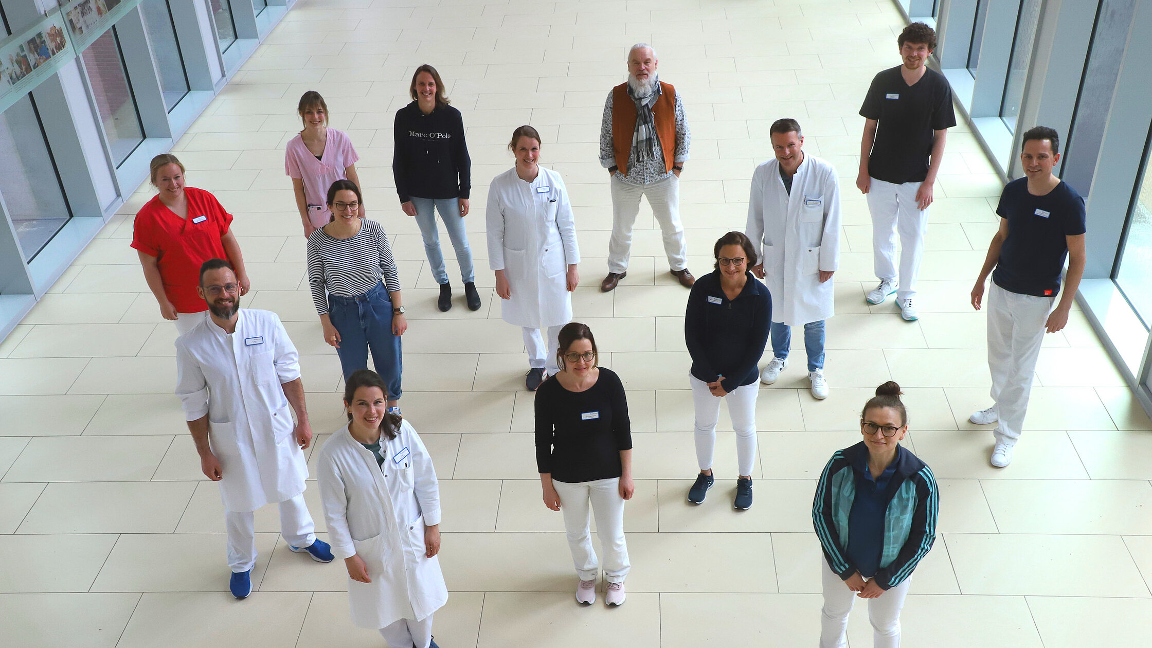Mehrere Mitarbeitende der Kinder- und Jugendrheumatologie stehen in einem hellen Klinikflur und blicken zur Kamera.