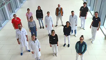 Mehrere Mitarbeitende der Kinder- und Jugendrheumatologie stehen in einem hellen Klinikflur und blicken zur Kamera.