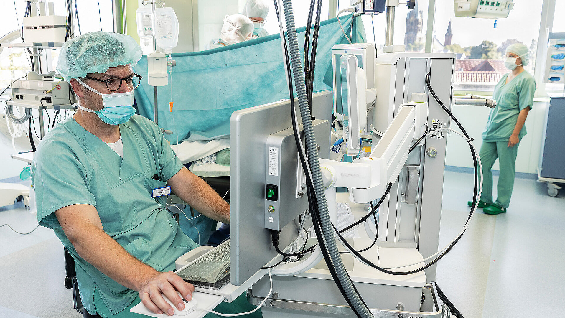 Chefarzt Dr. med. Matthias Boschin sitzt im Operationssaal an einem Monitor und steuert die Narkoseüberwachung.