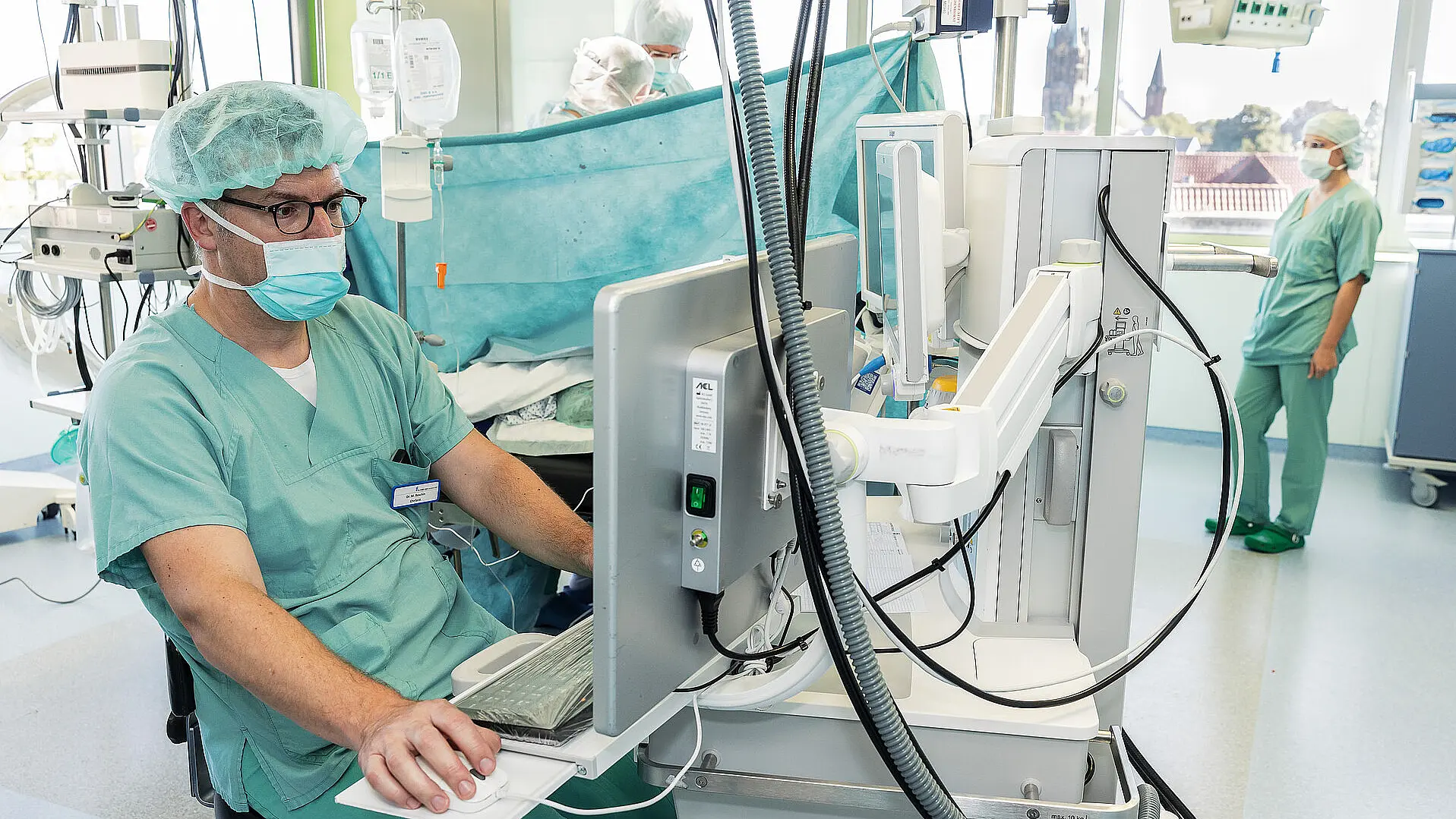 Chefarzt Dr. med. Matthias Boschin sitzt im Operationssaal an einem Monitor und steuert die Narkoseüberwachung.