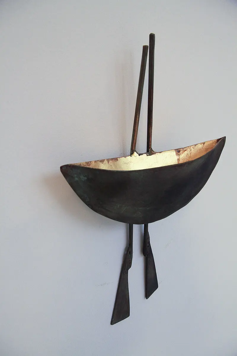 Wandmontiertes Kunstobjekt in Bootsform aus dunklem Metall mit hell gestalteter Innenfläche.