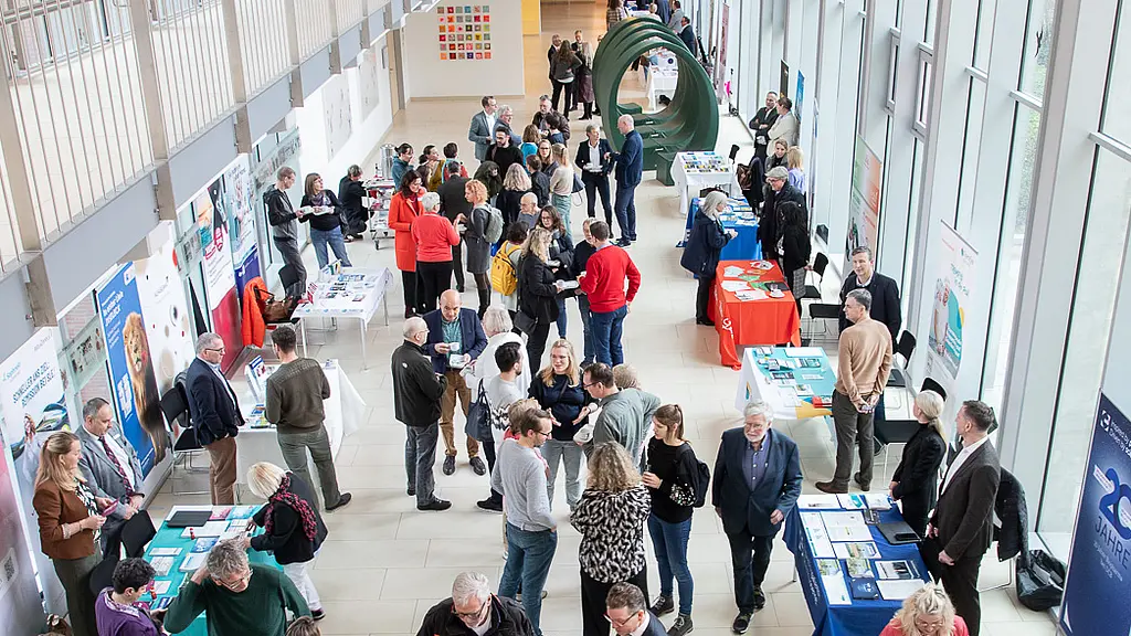 Menschen stehen an Informationsständen in der Magistrale und unterhalten sich miteinander.