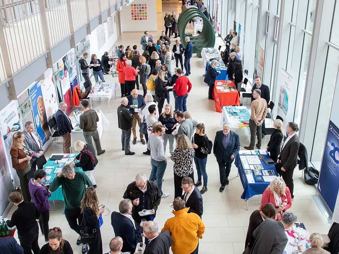 Blick von oben in die Magistrale des St. Josef-Stifts: Besucherinnen und Besucher stehen an Infotischen und tauschen sich bei der Rheuma-Fortbildung Adventssymposium aus.