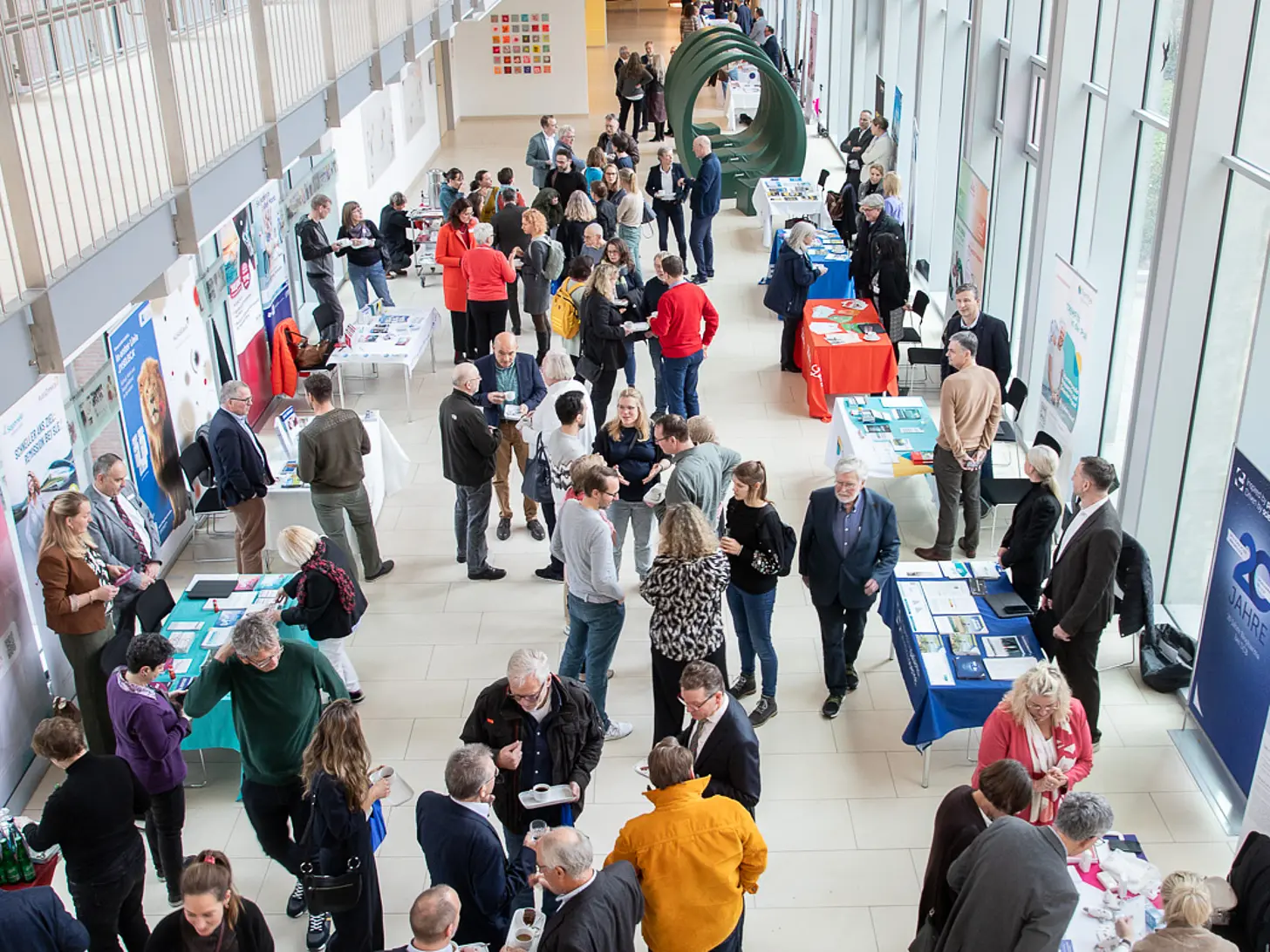 Blick von oben in die Magistrale des St. Josef-Stifts: Besucherinnen und Besucher stehen an Infotischen und tauschen sich bei der Rheuma-Fortbildung Adventssymposium aus.