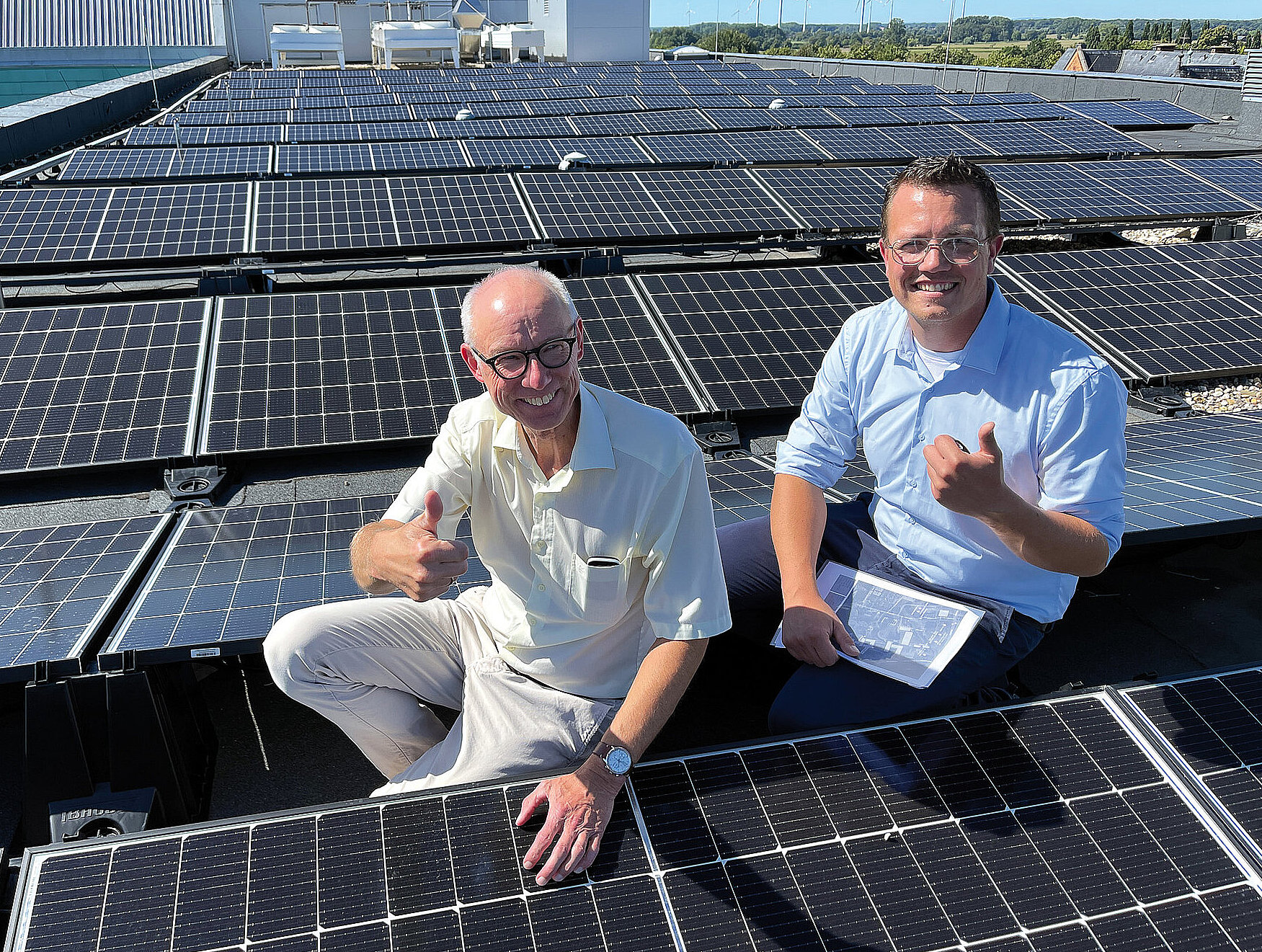Photovoltaikmodule auf Flachdächern mit zwei Männern und Daumen hoch