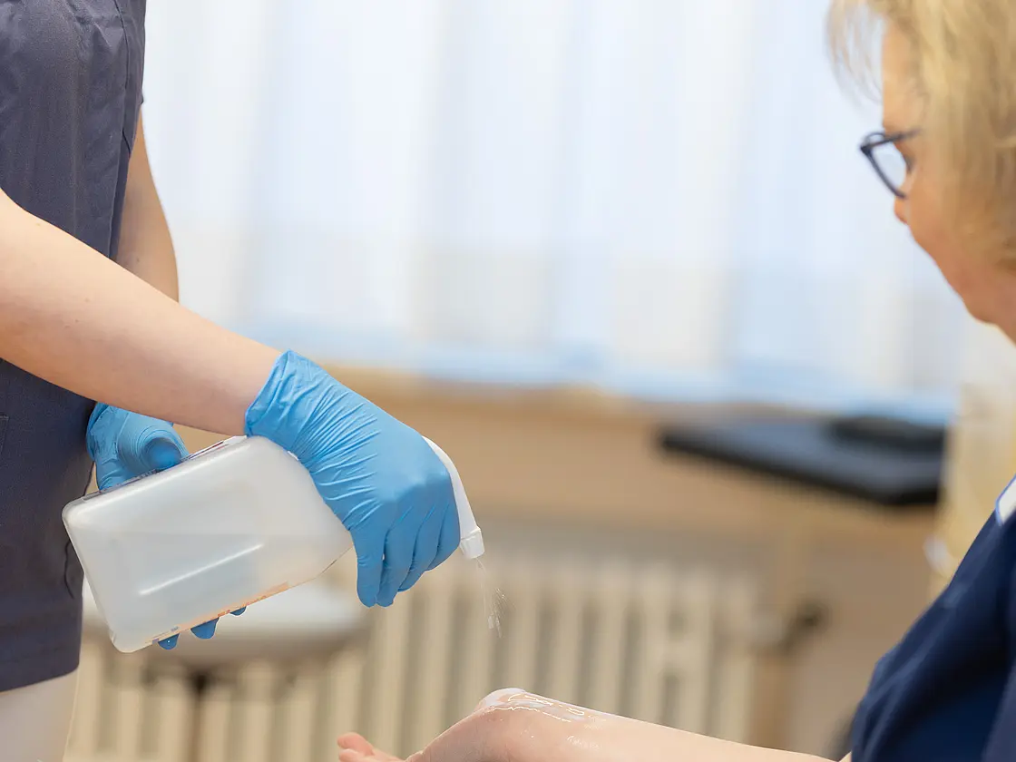 Eine Medizinische Fachangestellte sprüht einer Patientin Desinfektionsm