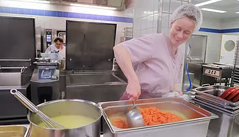 Mitarbeiterin der Küche kocht in einer professionellen Großküche.