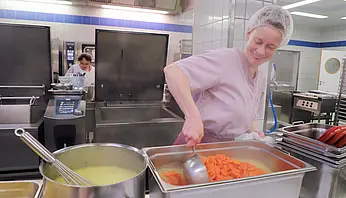 Mitarbeiterin der Küche kocht in einer professionellen Großküche.