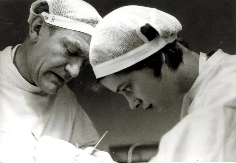 Zwei Ärzte arbeiten gemeinsam konzentriert während eines operativen Eingriffs, aufgenommen in Schwarzweiß.