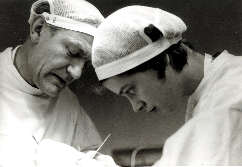 Zwei Ärzte arbeiten gemeinsam konzentriert während eines operativen Eingriffs, aufgenommen in Schwarzweiß.