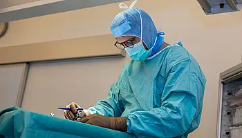 Operateur arbeitet während eines laufenden ambulanten chirurgischen Eingriffs konzentriert am OP-Tisch.