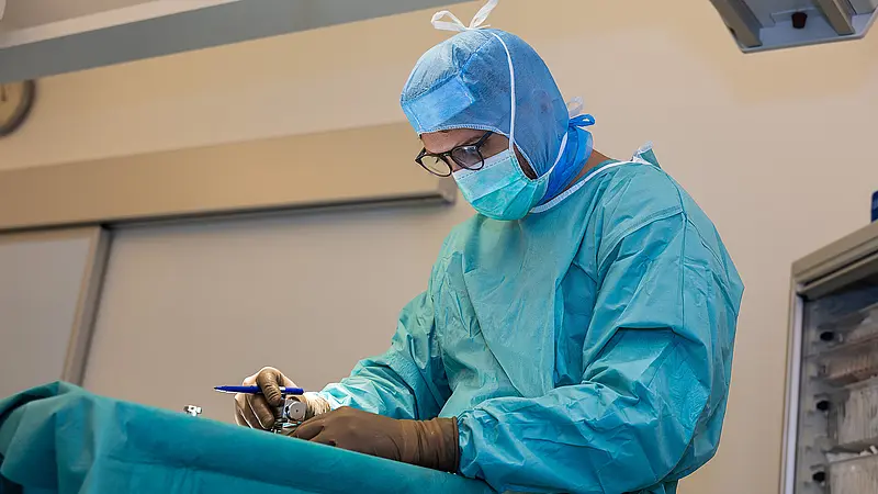 Operateur arbeitet während eines laufenden ambulanten chirurgischen Eingriffs konzentriert am OP-Tisch.