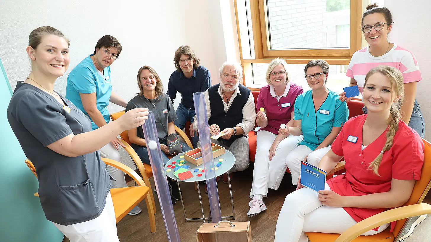 Mehrere Mitarbeitende des psychosozialen Teams sitzen gemeinsam in einem Besprechungsraum und zeigen Materialien aus der therapeutischen und beratenden Arbeit.