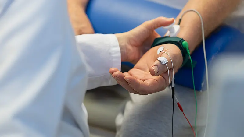 Hand eines Patienten mit angeschlossenen Elektroden während einer neurologischen Messung.