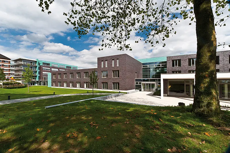 Moderner Klinikbau mit Glasfassade und Grünflächen auf dem Campus des St. Josef-Stift Sendenhorst.