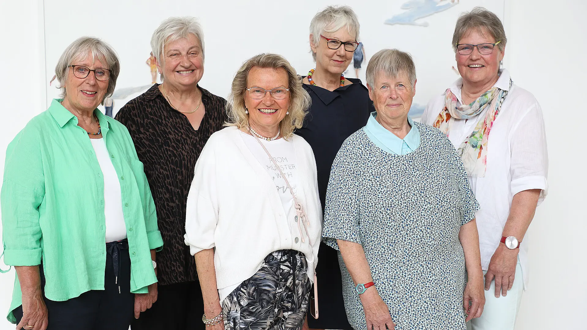 Mehrere Personen stehen als Gruppe in einem hellen Innenraum.