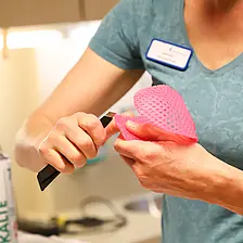 Nahaufnahme: Eine Ergotherapeutin schneidet und formt thermoplastisches Material für eine maßgefertigte Handschiene.