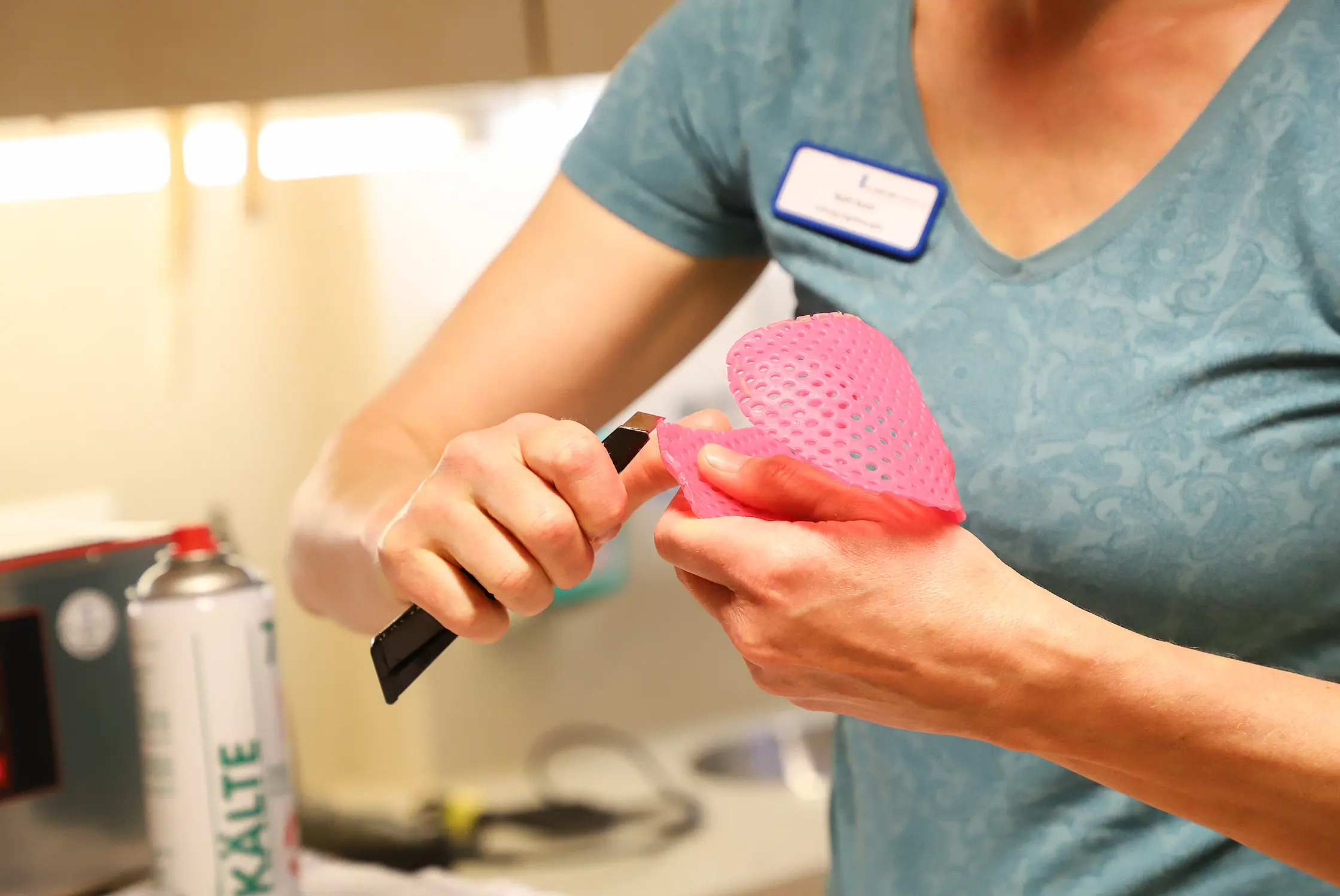 Nahaufnahme: Eine Ergotherapeutin schneidet und formt thermoplastisches Material für eine maßgefertigte Handschiene.