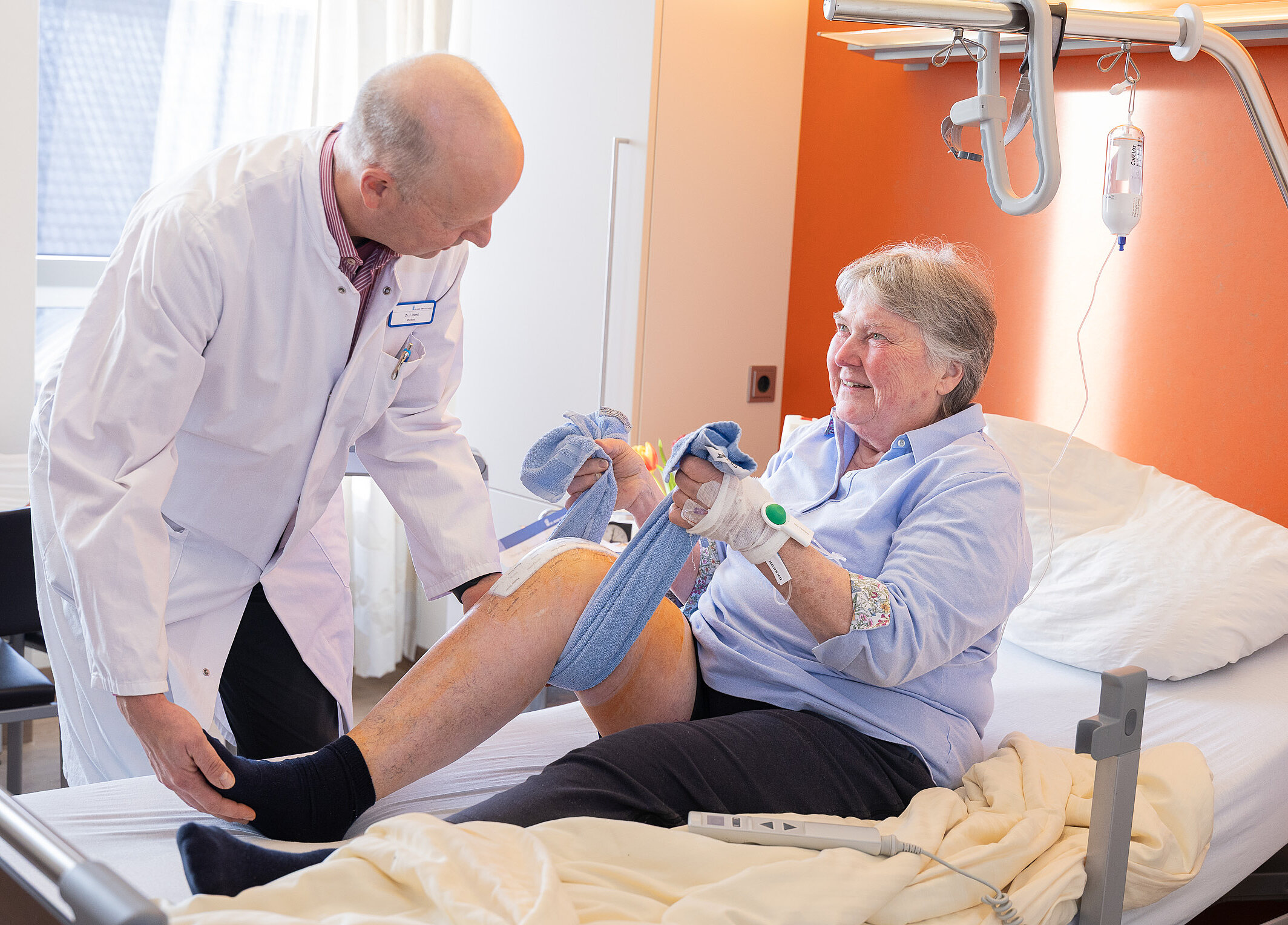 Aktivierende Pflege: Eine Patientin trainiert ihre Beinbeweglichkeit mit Unterstützung des ärztlichen Personals.