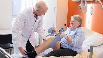 Aktivierende Pflege: Eine Patientin trainiert ihre Beinbeweglichkeit mit Unterstützung des ärztlichen Personals.