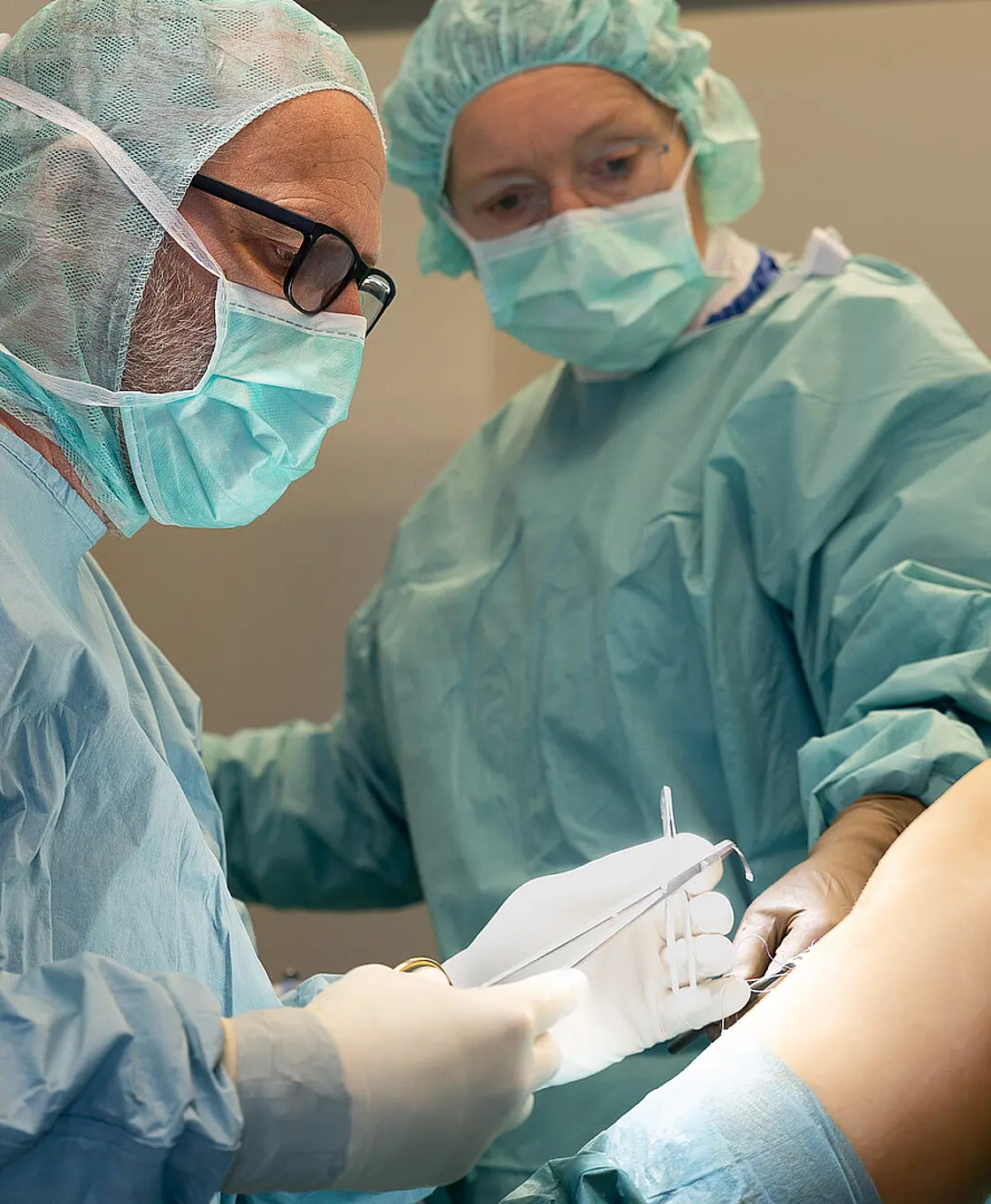 Zwei Mitarbeitende der Klinik für Ambulante Operationen & Sporttraumatologie führen einen ambulanten chirurgischen Eingriff an einem Knie durch.