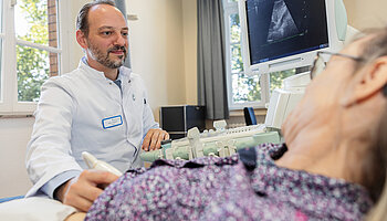 PD Dr. med. Peter Korsten führt mit einem Ultraschallgerät eine Untersuchung an der Hand einer Patientin durch.