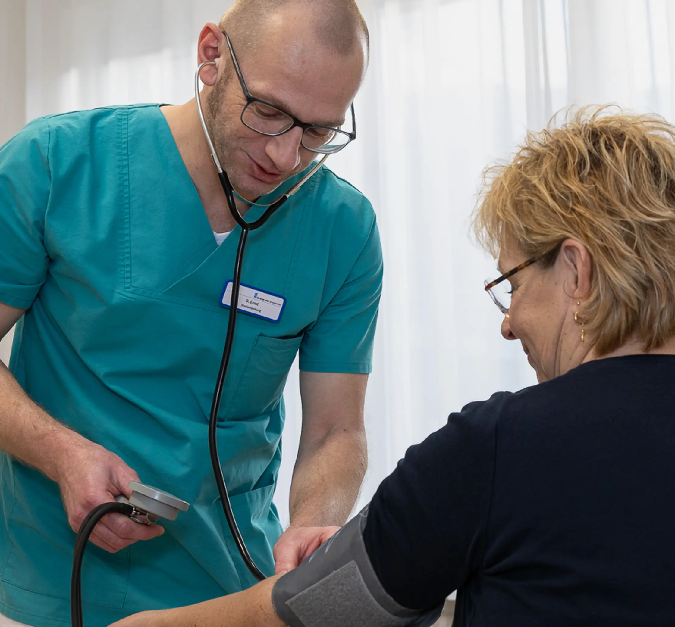 Ein Pfleger misst bei einer Patientin den Blutdruck.