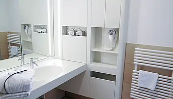 Waschbecken mit Spiegel, Ablageflächen und integrierten Staumöglichkeiten in heller Gestaltung.