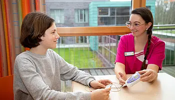 Elektroden sind an Armen angebracht, während ein kleines TENS-Gerät erklärt wird.