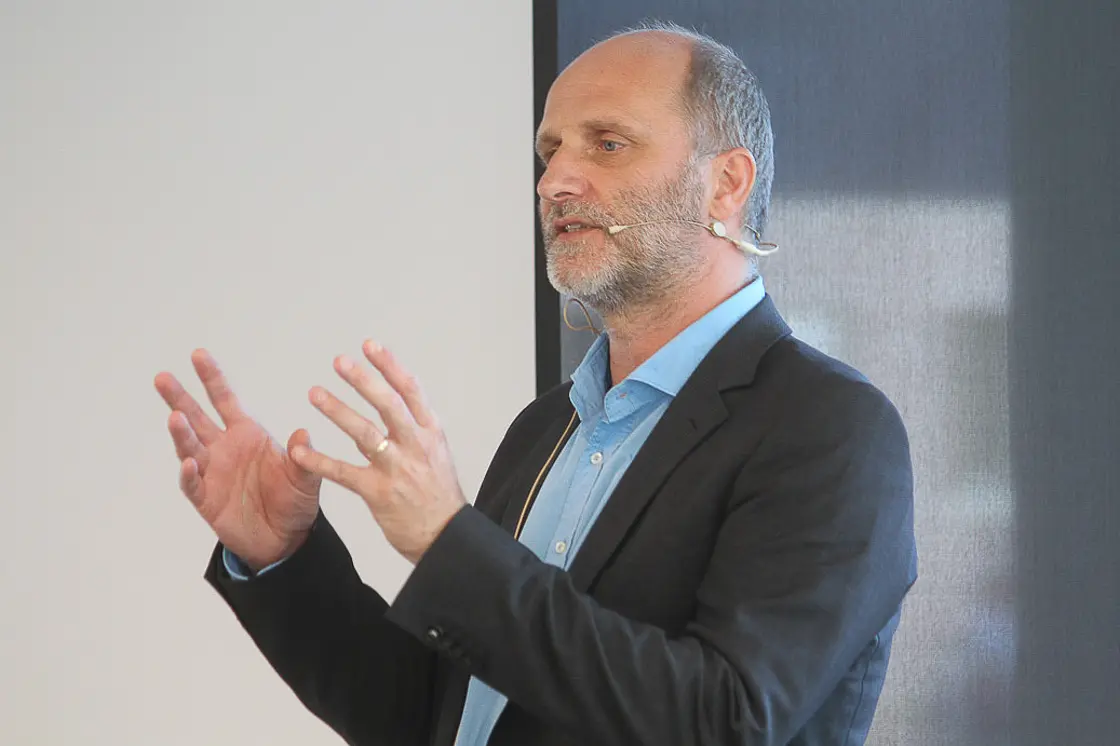 Chefarzt Dr. Carsten Radas hält bei der Patientenakademie einen Vortrag. Er spricht gestikulierend vor Publikum und trägt ein Headset-Mikrofon.