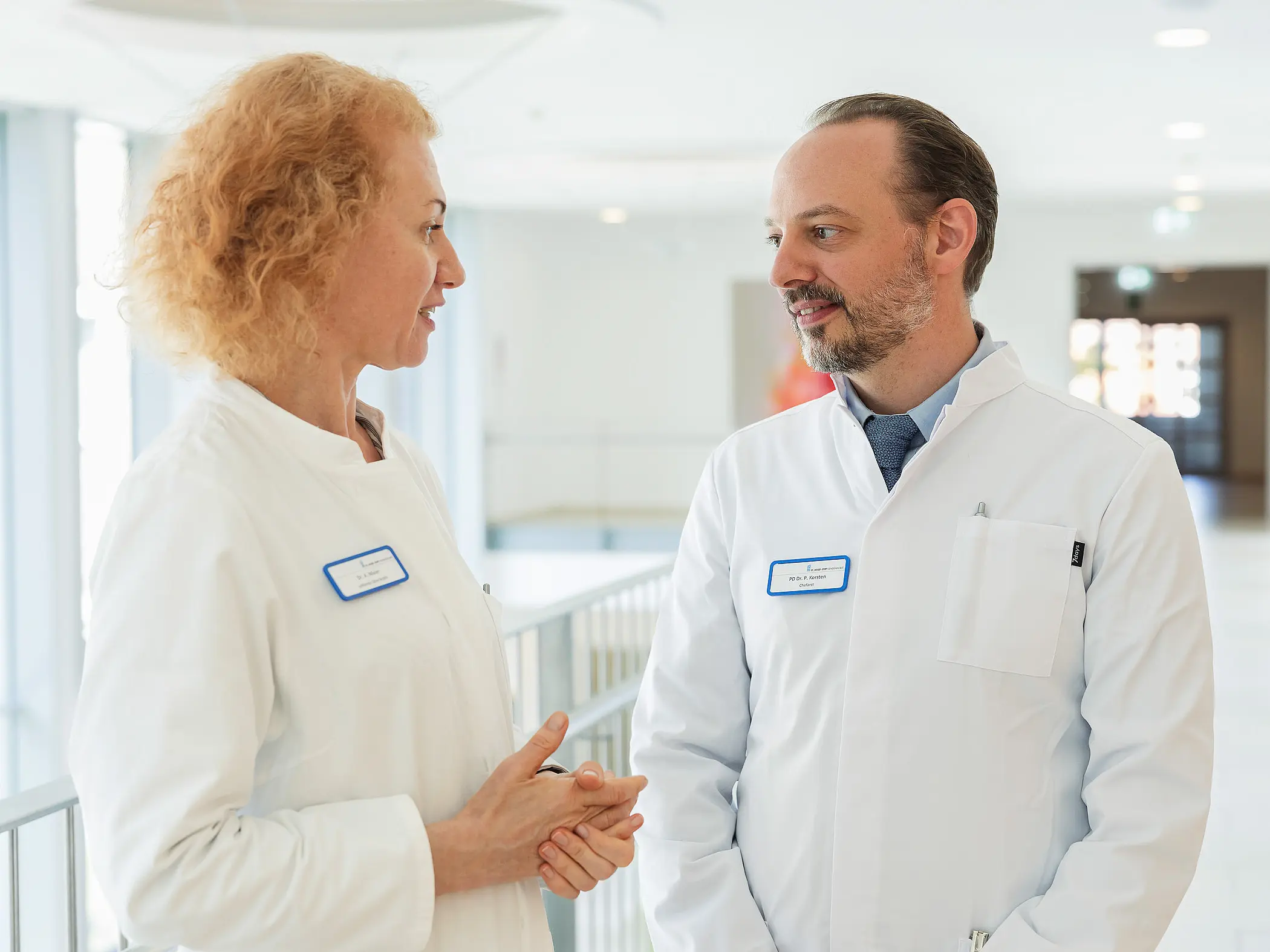 PD Dr. med. Peter Korsten spricht mit einer ärztlichen Kollegin in einem hellen Klinikflur.
