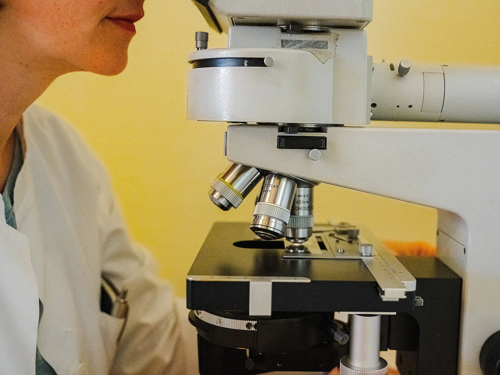 Detailaufnahme eines Labormikroskops mit Objektiv und Objekttisch.