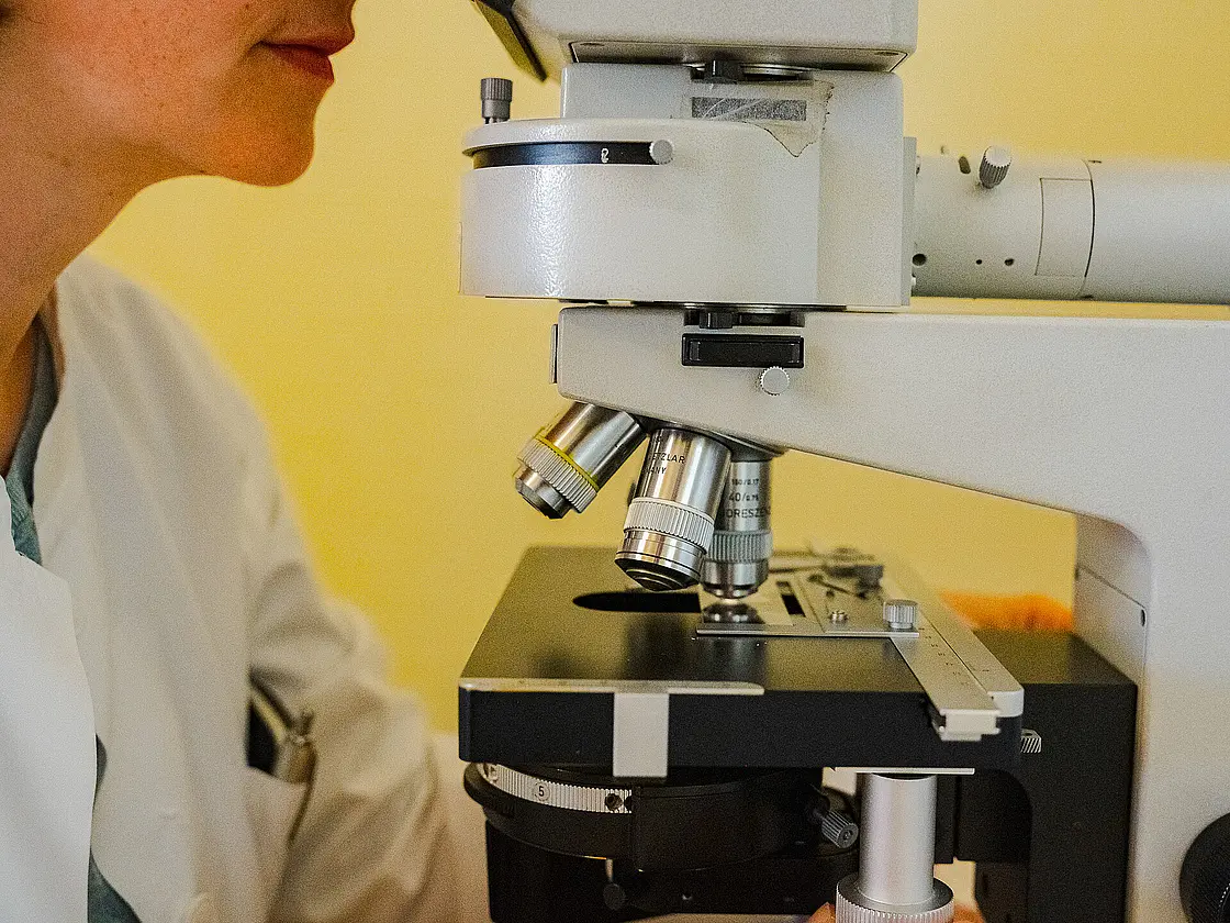 Detailaufnahme eines Labormikroskops mit Objektiv und Objekttisch.