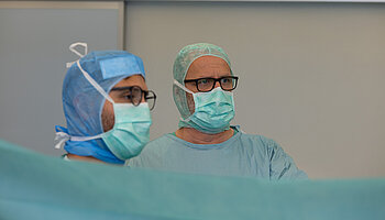 Zwei Operateure führen gemeinsam einen ambulanten chirurgischen Eingriff durch. Beide arbeiten konzentriert und koordiniert am OP-Tisch.