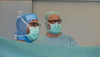 Zwei Operateure führen gemeinsam einen ambulanten chirurgischen Eingriff durch. Beide arbeiten konzentriert und koordiniert am OP-Tisch.