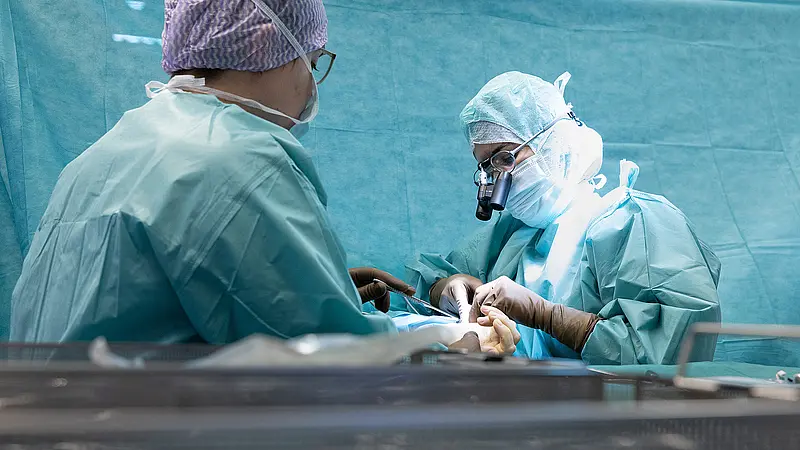 Zwei Operateure führen gemeinsam einen ambulanten chirurgischen Eingriff durch. Beide arbeiten konzentriert und koordiniert am OP-Tisch.