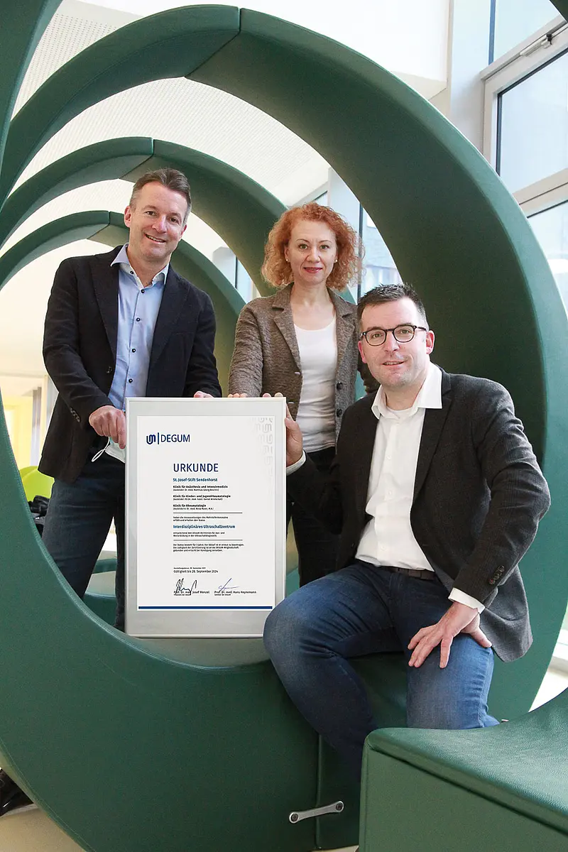 Drei Mitarbeitende des St. Josef-Stift Sendenhorst präsentieren eine Urkunde der Deutschen Gesellschaft für Ultraschall in der Medizin zur Zertifizierung als interdisziplinäres Ultraschallzentrum.