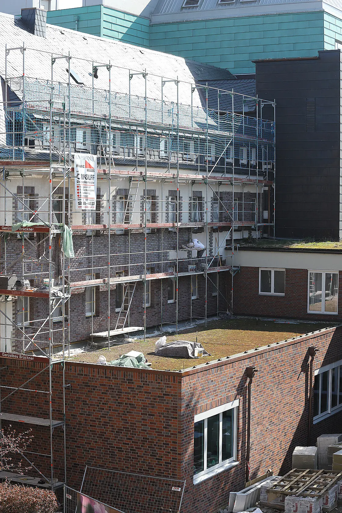 Gebäudefassade während energetischer Sanierungsarbeiten mit Baugerüst und gesicherter Arbeitsfläche.