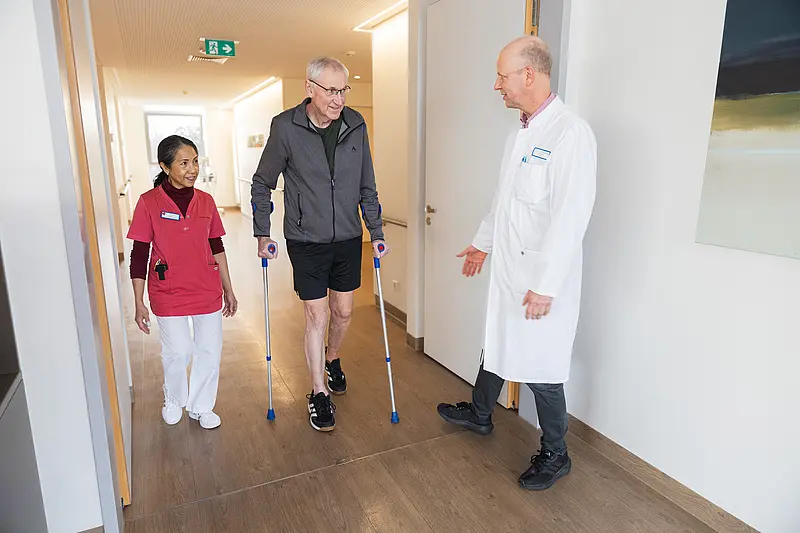 Aktivierende Pflege: Eine Patientin trainiert ihre Beinbeweglichkeit mit Unterstützung des ärztlichen Personals.