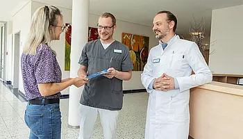 PD Dr. med. Peter Korsten steht mit Mitarbeitenden und Patientin im Klinikflur im Austausch.