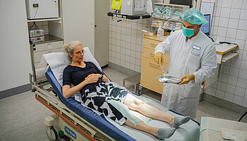 Medizinisches Fachpersonal versorgt das Bein einer Patientin im ambulanten Behandlungsraum.