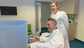 Dr. PD Daniel Windschall und eine Ärztin stehen vor einem Ultraschallgerät und betrachten gemeinsam die Bilddarstellung auf dem Monitor.