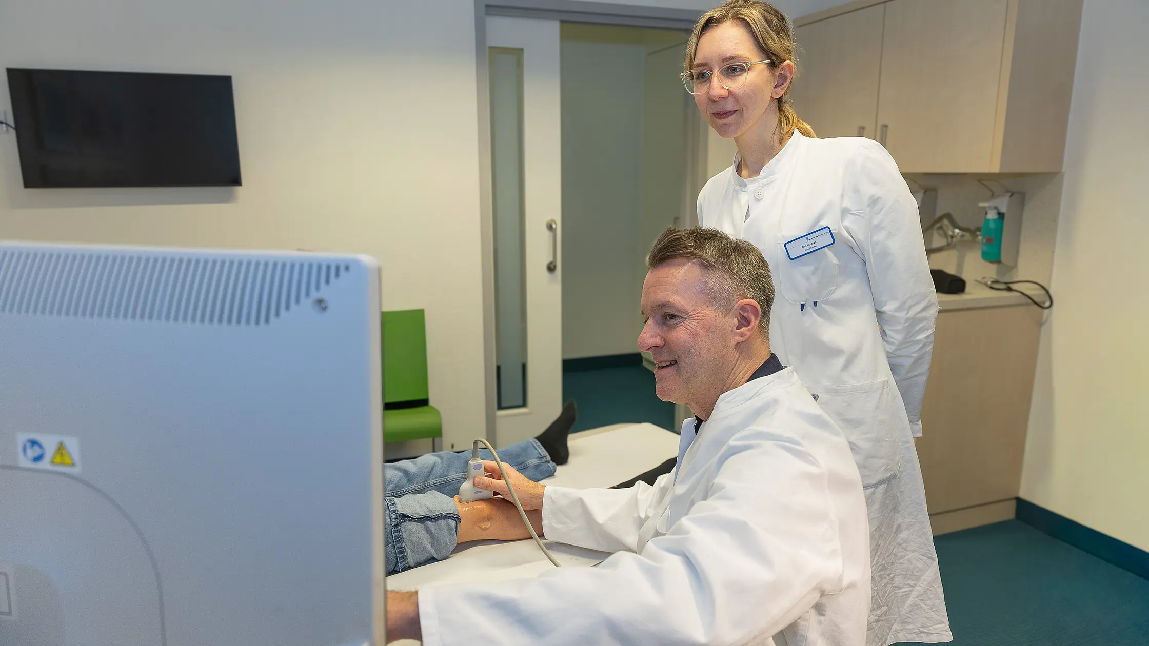 Dr. PD Daniel Windschall und eine Ärztin stehen vor einem Ultraschallgerät und betrachten gemeinsam die Bilddarstellung auf dem Monitor.