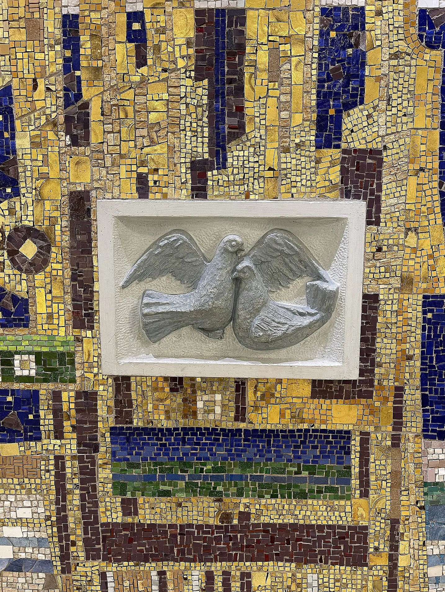 Detailansicht eines Wandmosaiks im Spithöver Forum mit gold- und farbigen Steinflächen sowie einem zentralen Relief aus zwei einander zugewandten Tauben.