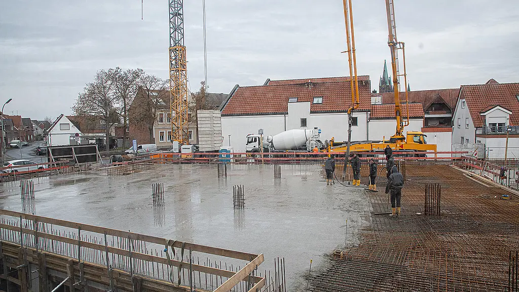 Bauarbeiter stehen auf einem großen Feld mit frischem Beton.