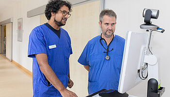 Ein Arzt und ein Intensivpfleger nutzen einen telemedizinischen Monitor zur gemeinsamen intensivmedizinischen Fallbesprechung.