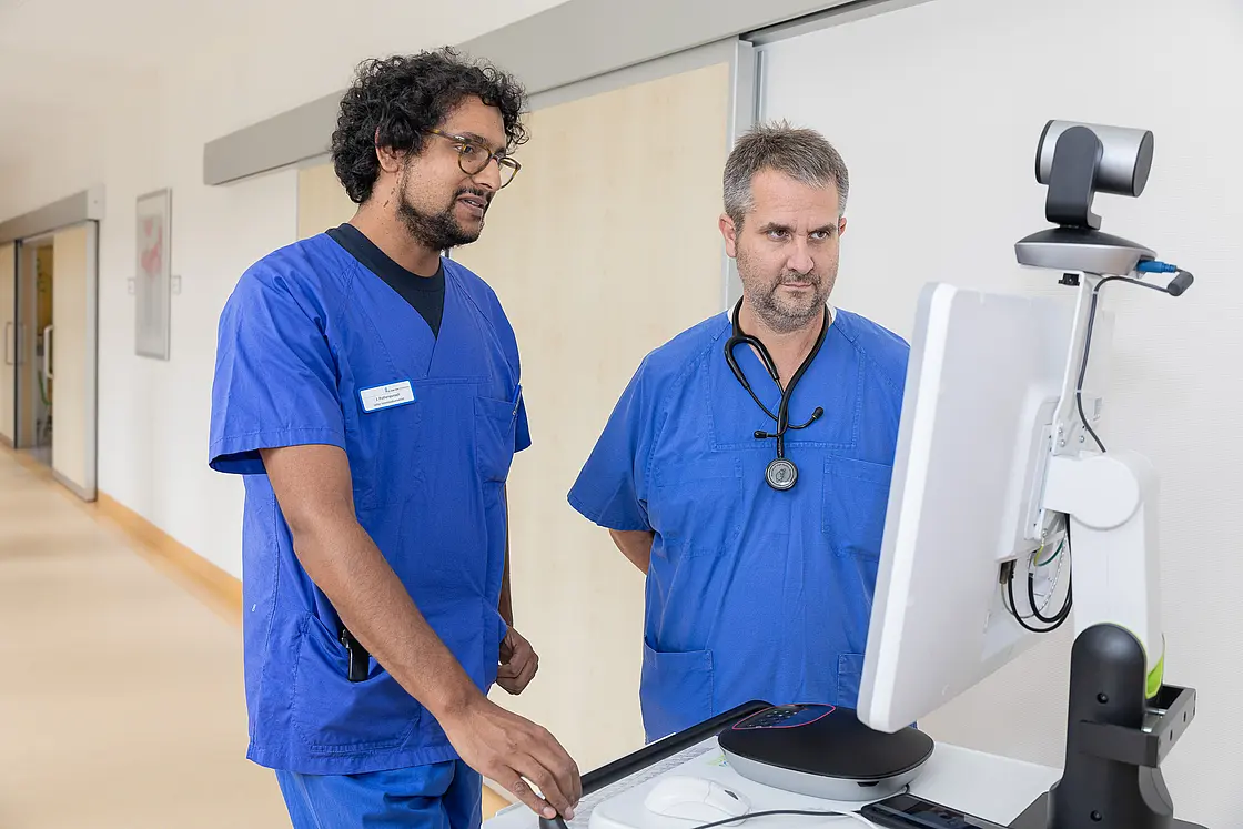 Ein Arzt und ein Intensivpfleger nutzen einen telemedizinischen Monitor zur gemeinsamen intensivmedizinischen Fallbesprechung.