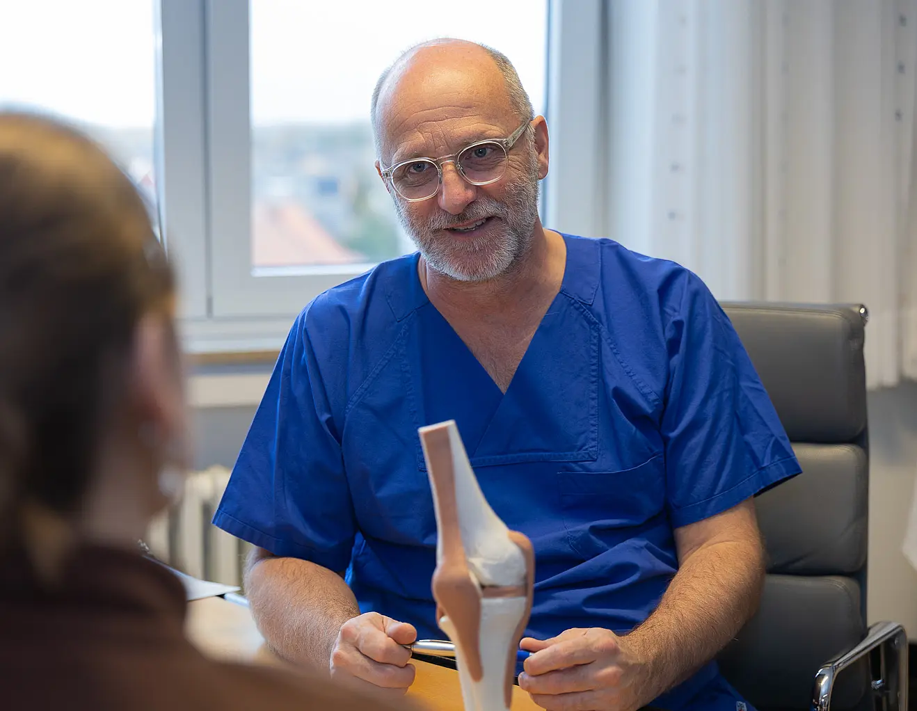 Dr. Carsten Radas im Gespräch mit Patientin am Knie-Modell