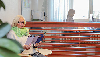 Eine Patientin sitzt im Empfangsbereich der Klinik für Ambulante Operationen & Sporttraumatologie.